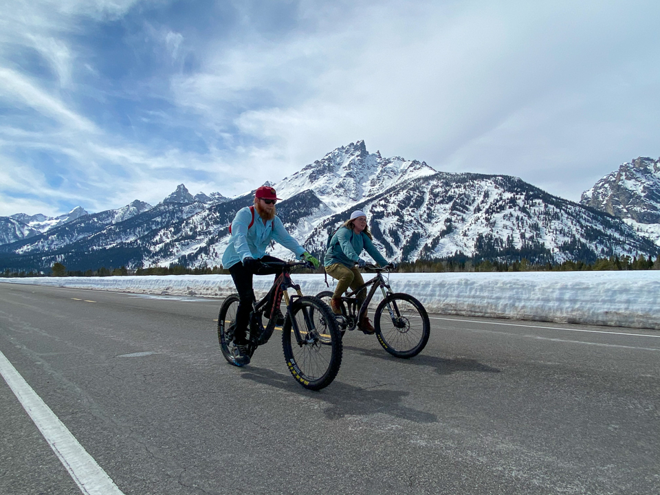 Bicyclists ride on the plowed Teton Park Road with the Teton Range in the background