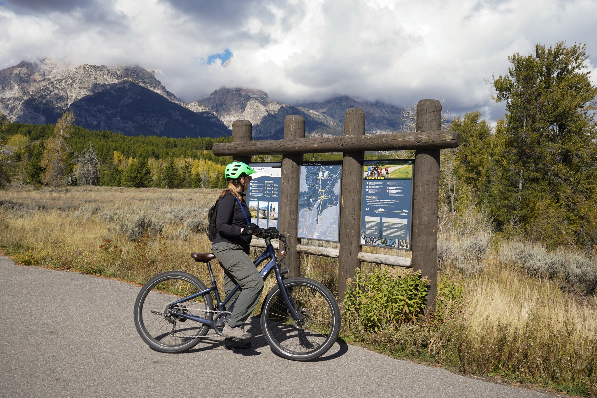 a biker looks at signs on a paved path