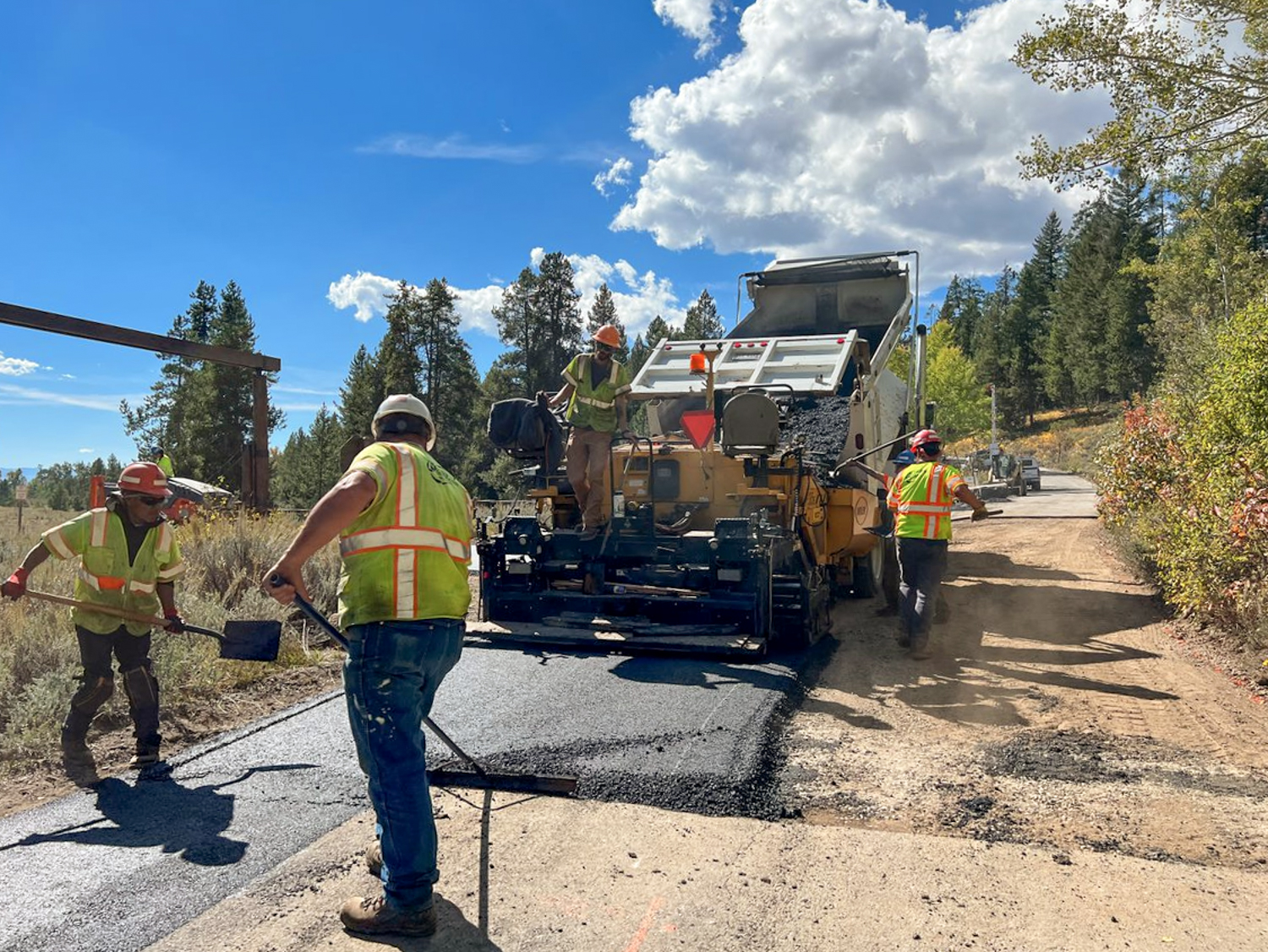 Construction crews pave the dirt portion of the Moose-Wilson Road