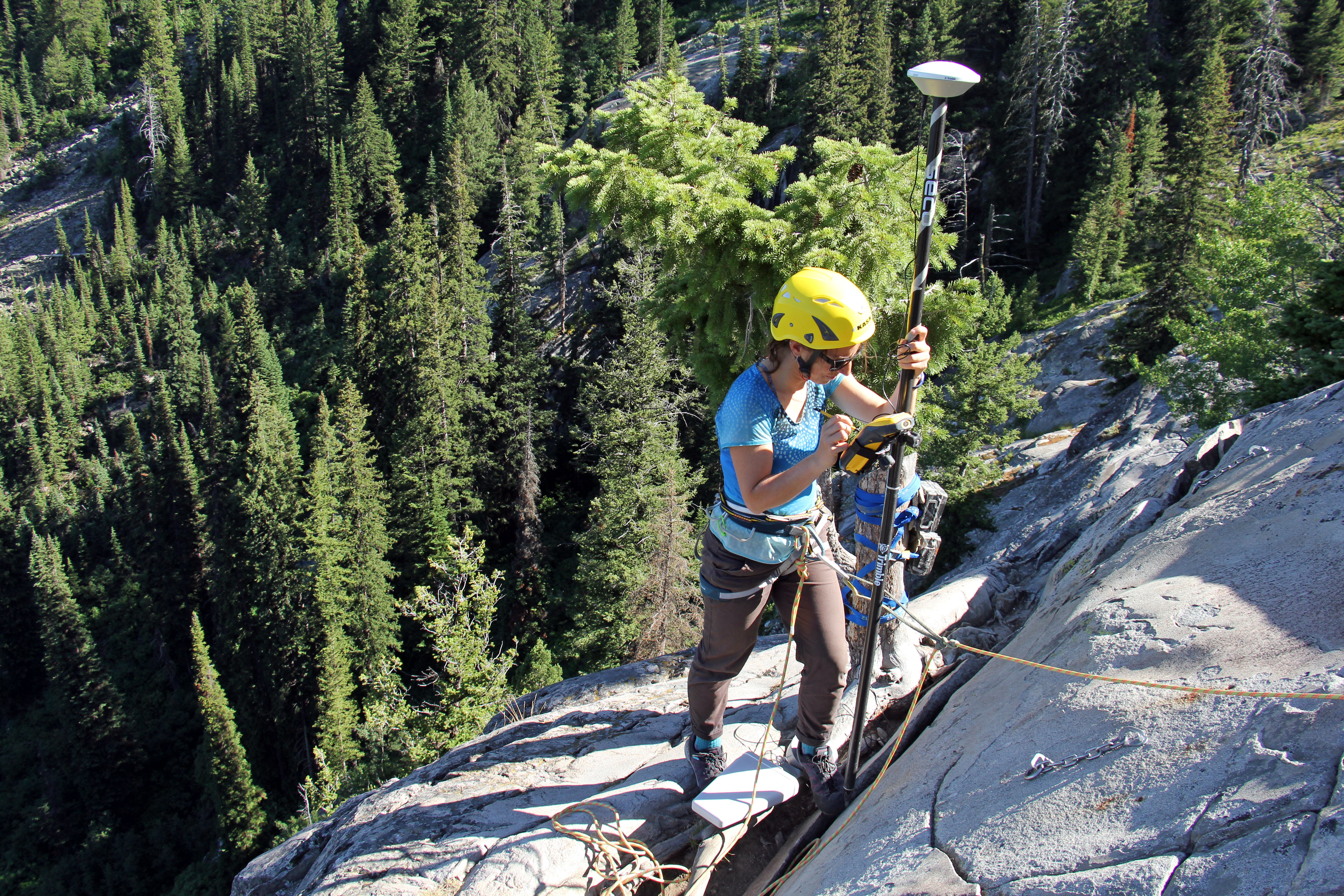 A Grand Teton National Park physical scientist takes a GPS reading along the crack in the rock buttress.