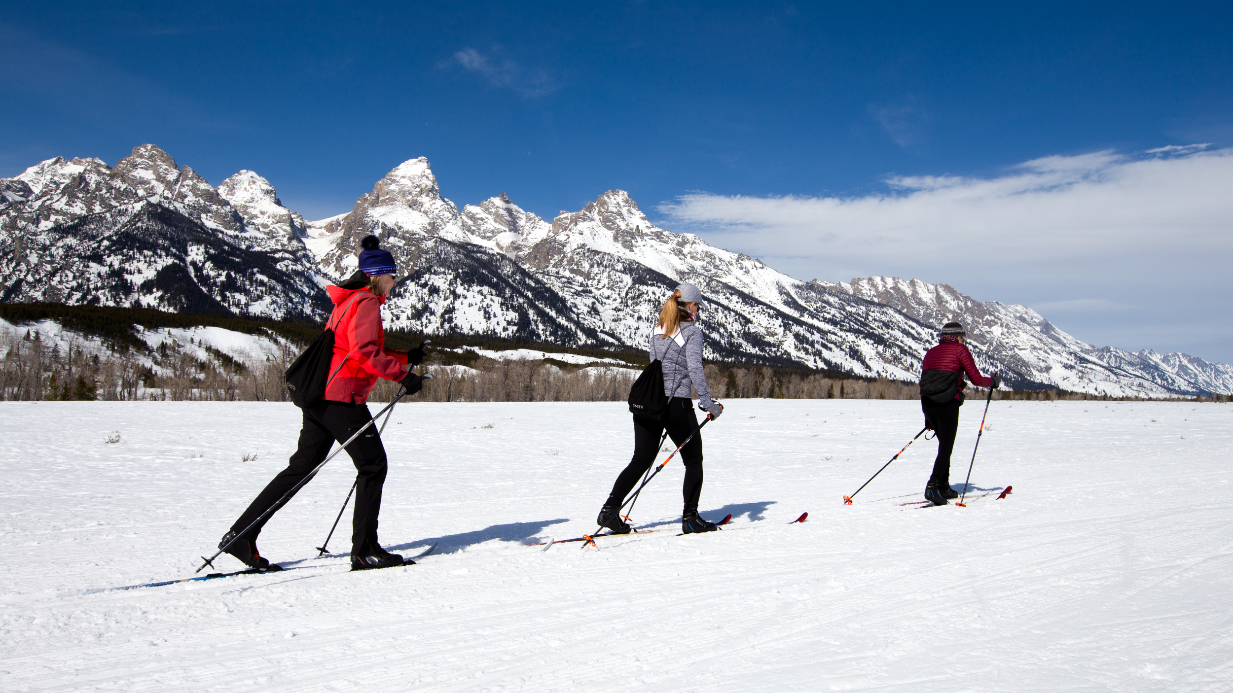 Cross-country skiers ski the Teton Park Road with the snowy Teton Range behind