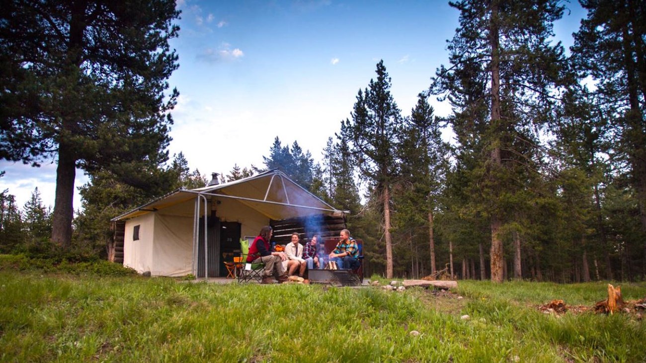 Campers enjoying fire in front of a Tent Cabin