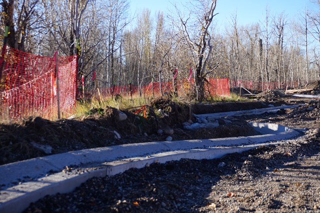 Construction fencing alongside newly installed road curbs.