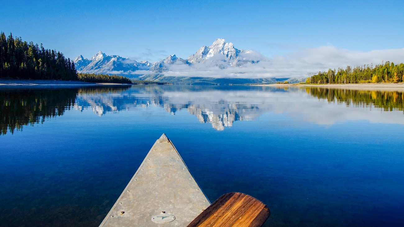 Boating on Jackson Lake with clear blue waters reflecting the Teton Mountain Range