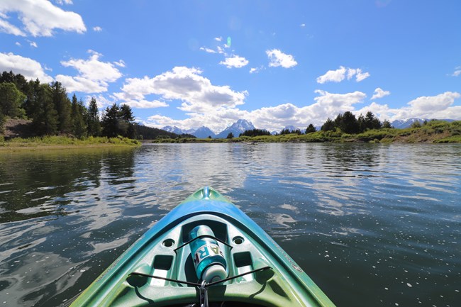 The front of a kayak on a river.