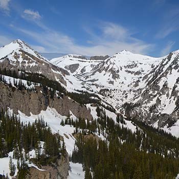 A mountainous canyon covered in patchy snow.