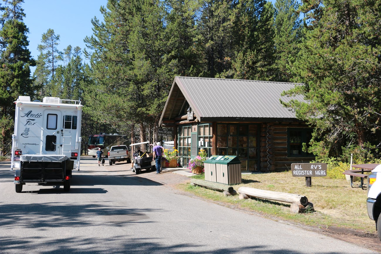 An RV beside a log building.