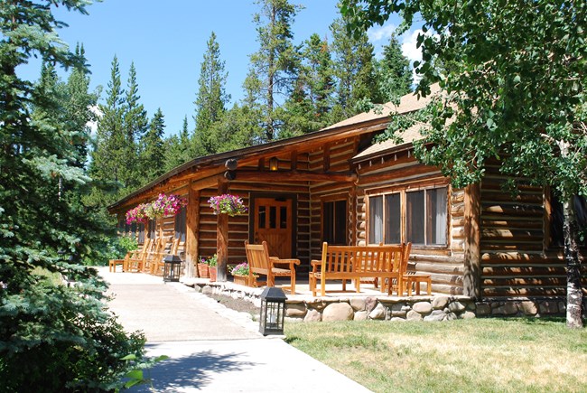 A wood building with chairs on a porch.