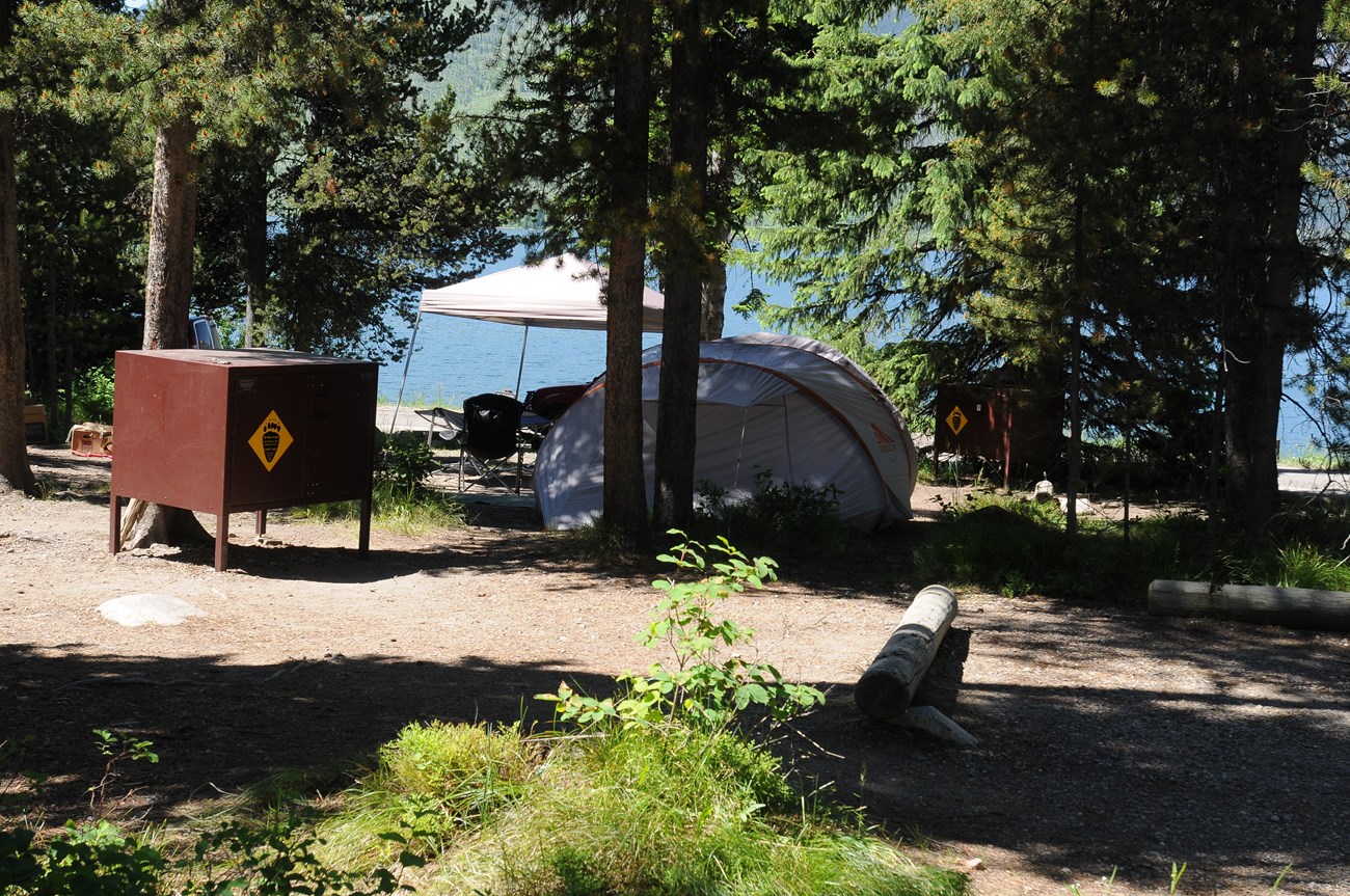 A tent in a campsite by a lake.