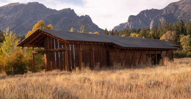 A wood cabin with mountains in the background.