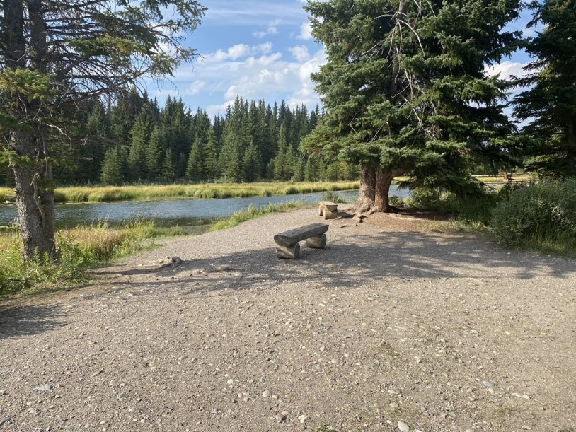 Gravel walkway with benches and a view of a river.