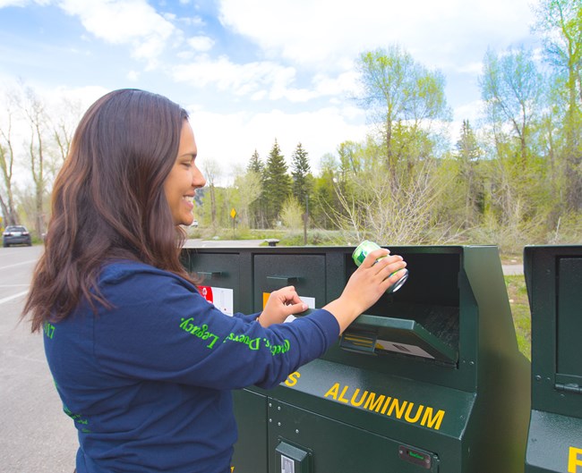 Recycle Woman throwing a aluminum can into a recycling container.