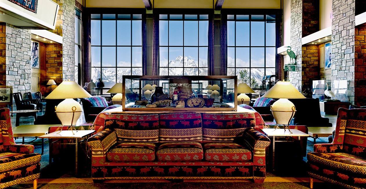 A hotel lobby with mountains viewed through the windows.