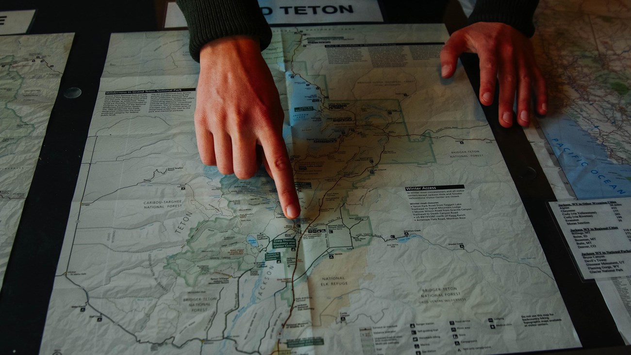 A ranger pointing to the visitor center on the map of the park
