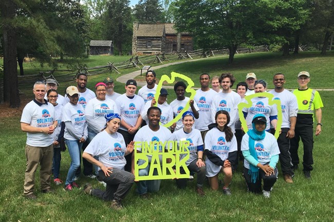 Volunteers pose with rangers in front of historic farm