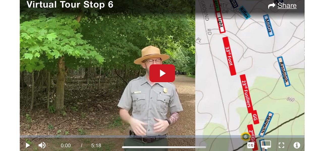 Virtual Tour with Ranger Jason A Park ranger stands next to a digital map superimposed on the battlefield