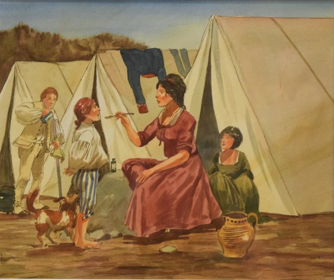A woman and three children sit in an 18th century Revolutionary War camp surrounded by three triangular tents. The woman feeds one child with a spoon.