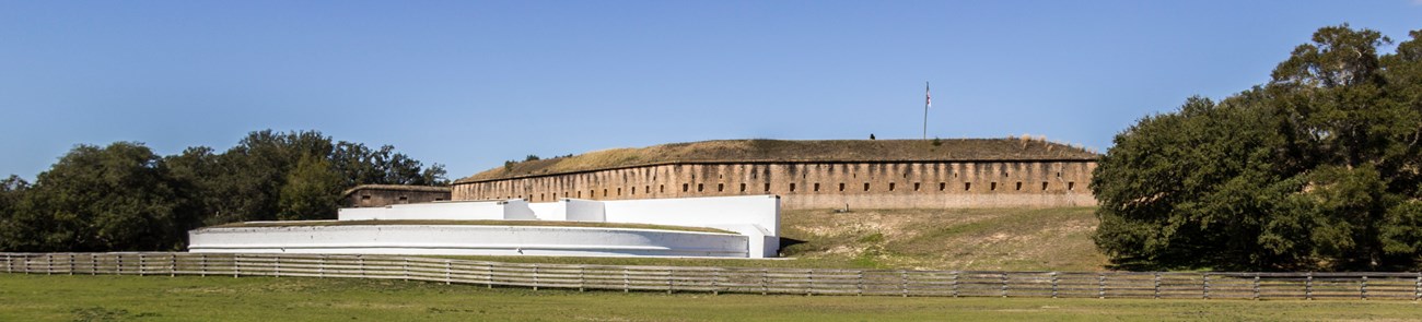Two large masonry forts stand on a hill below a blue sky