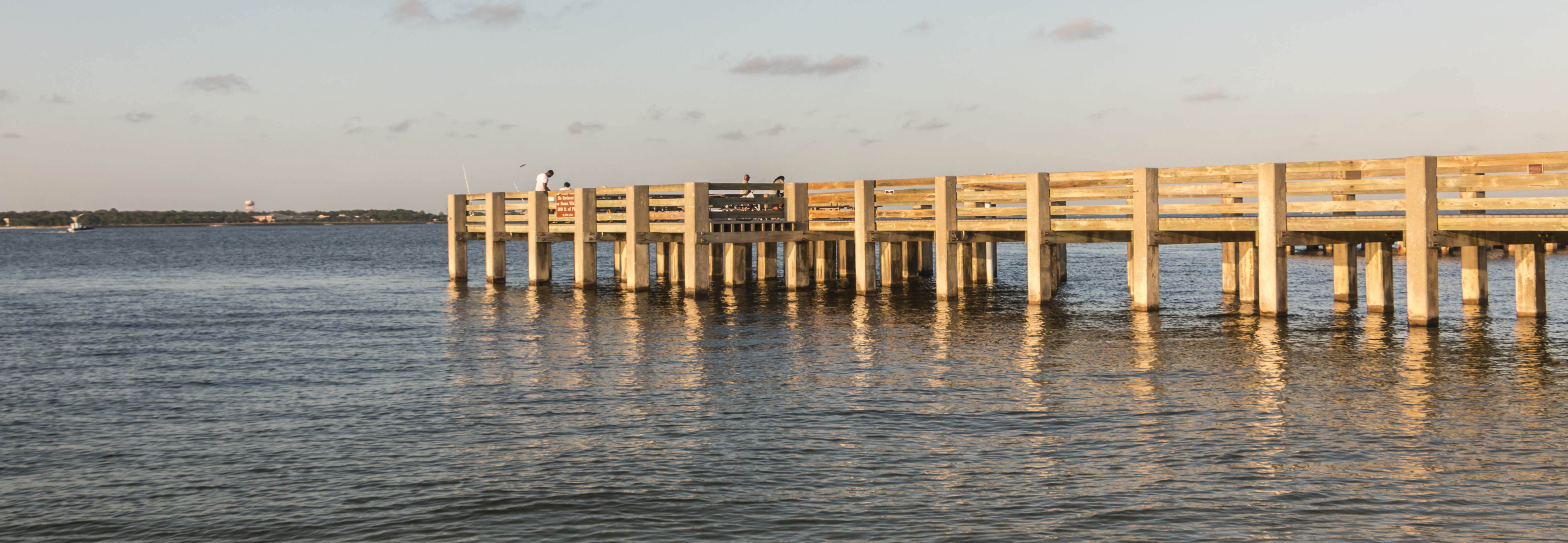 A concrete and wooden fishing pier extends into the water. A concrete and wooden fishing pier extends into the water.