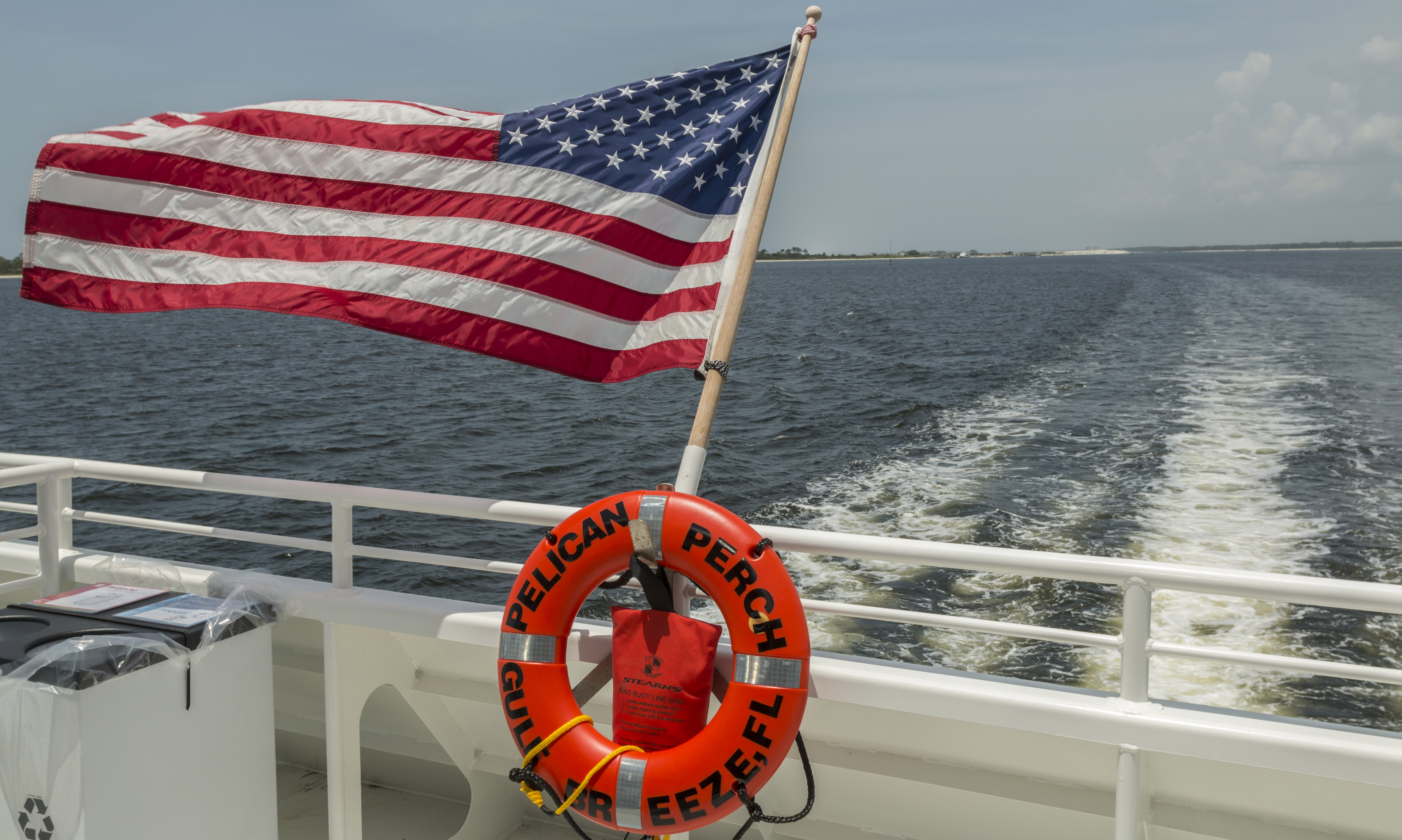 Pelican Perch underway. An american flag flys from the back of a tour boat.