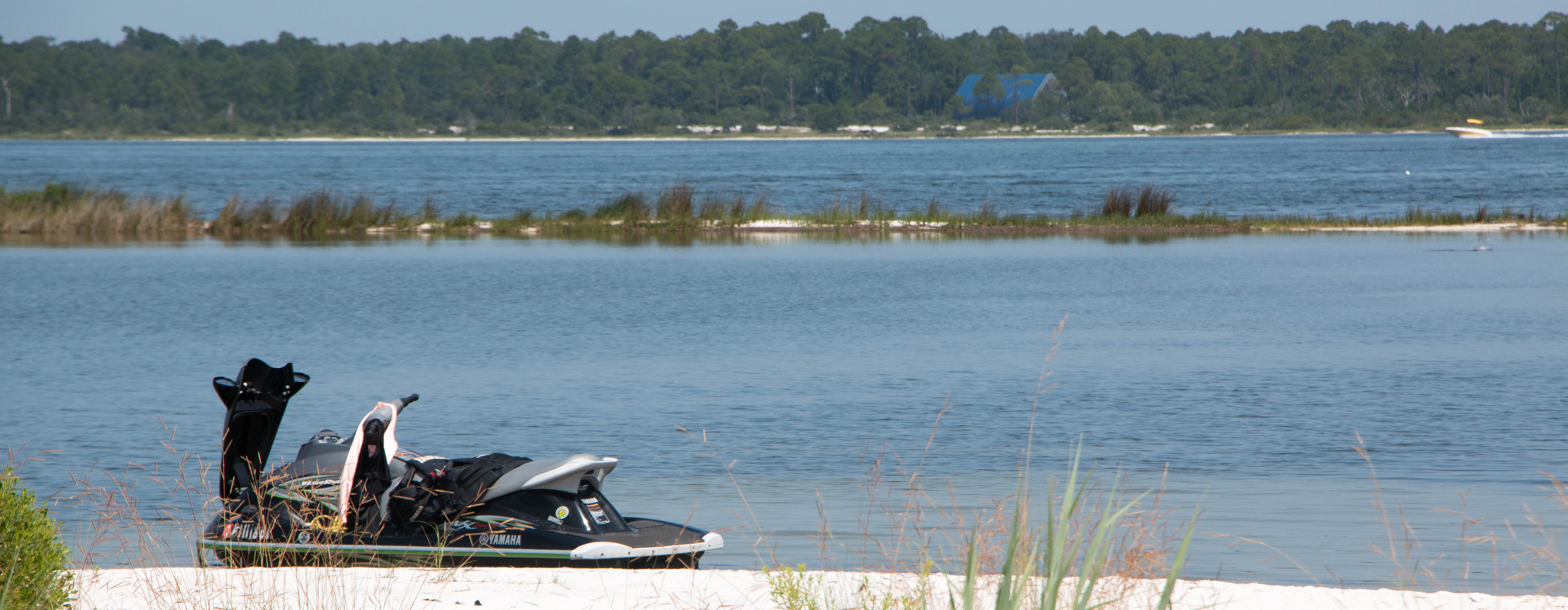 A personal watercraft sits on a the edge of a beach. A personal watercraft sits on a the edge of a beach.