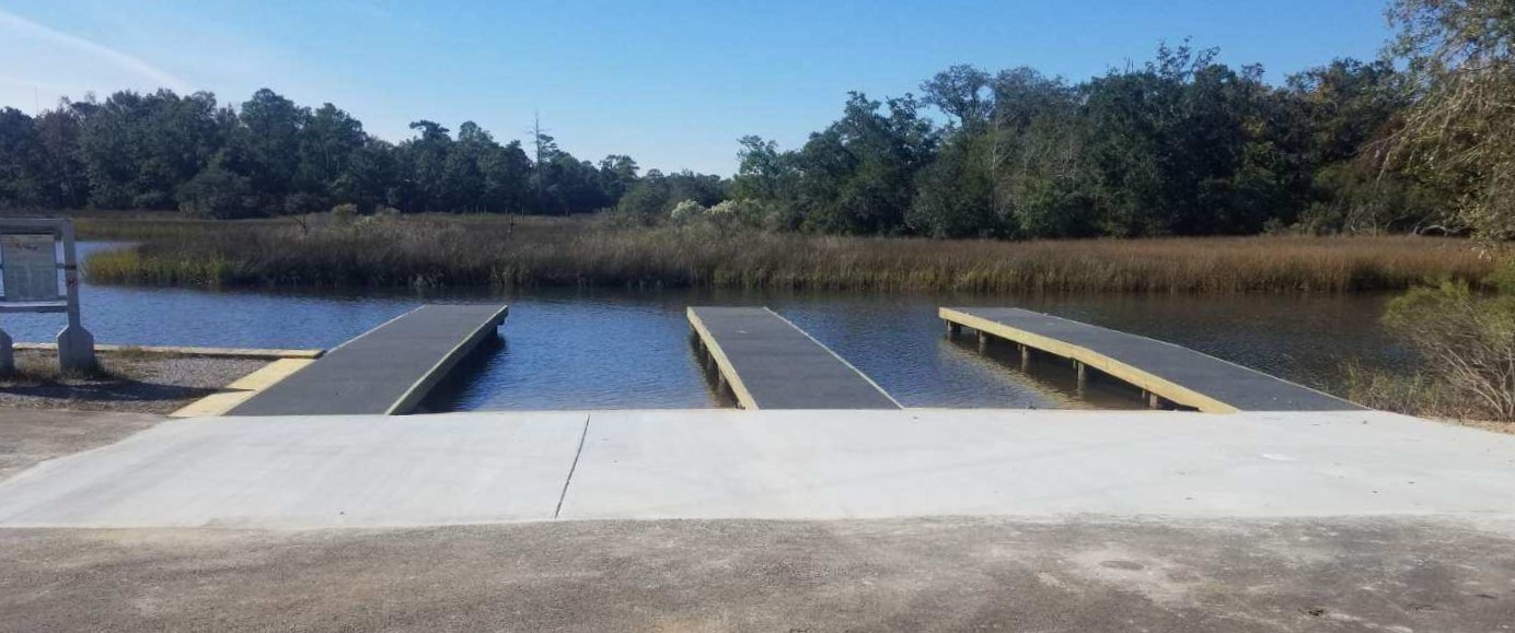 Finger piers extend out into a bayou with a salt marsh and maritime forest in the background.