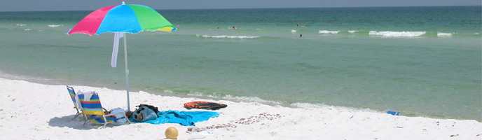 Beach chairs and an umbrella are setup near the water. Beach chairs and an umbrella are setup near the water.