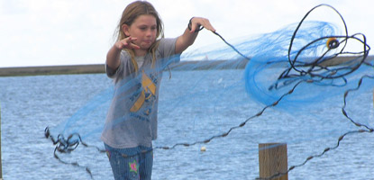 A young visitor expertly throws her 5 foot blue cast net, causing it to open in a perfect circle. A young visitor expertly throws her 5 foot blue cast net, causing it to open in a perfect circle.