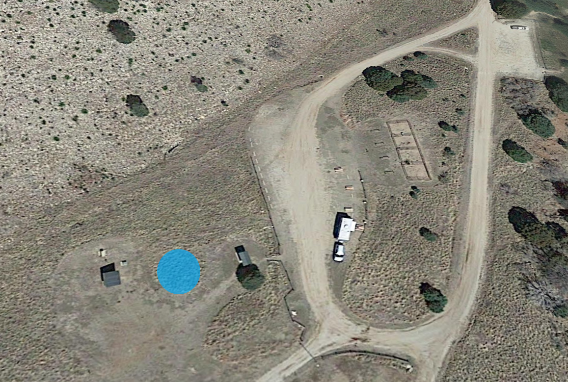 Assembly and distribution area marked by blue circle in between the trailhead sign and a small well house.