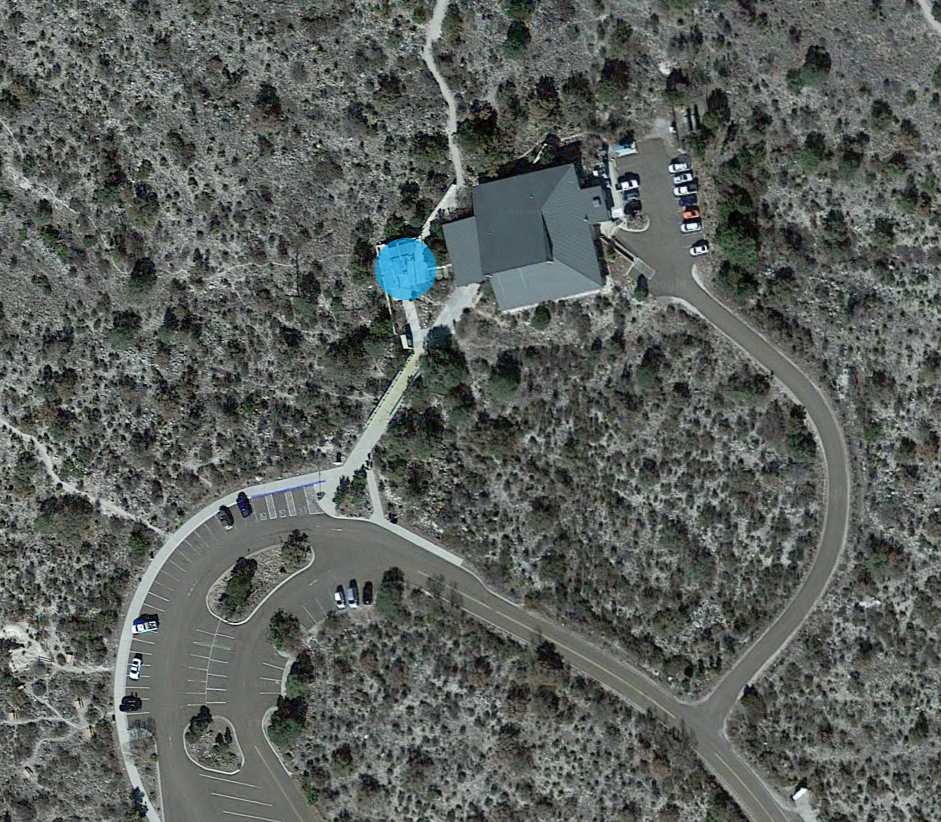 Assembly and distribution area marked by blue circle at the front patio and pergola located in front of the visitor center building.