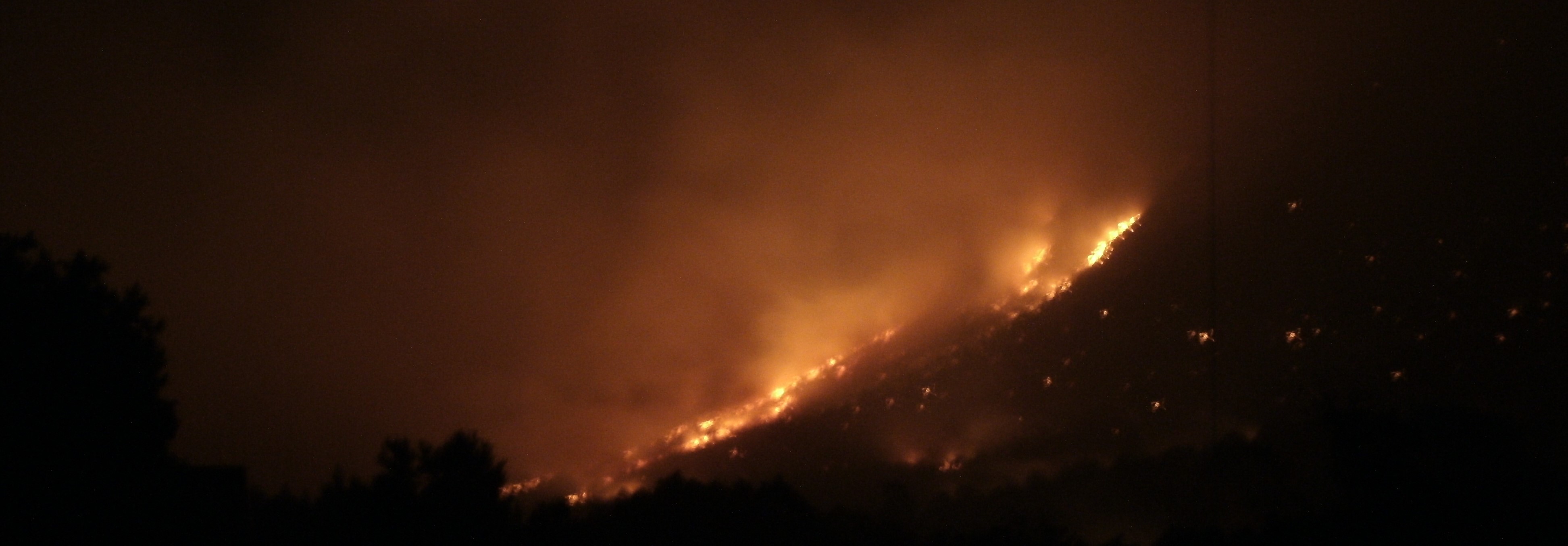 Dog Canyon Fire A fire burns across the mountain, lighting up the night with golden flames seen across the distance.