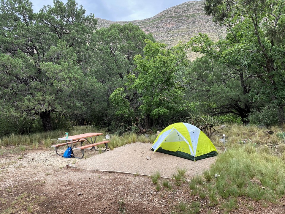 A yellow tent set up on a gravel tent pad