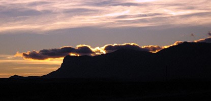 As the sun sets, the western sky behind the mountains is illuminated with color. As the sun sets, the western sky behind the mountains is illuminated with color.