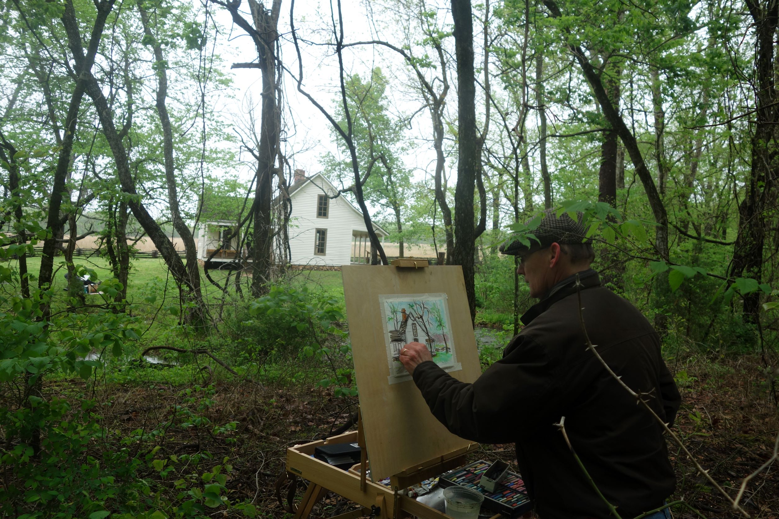 A man painting a house in woodlands.