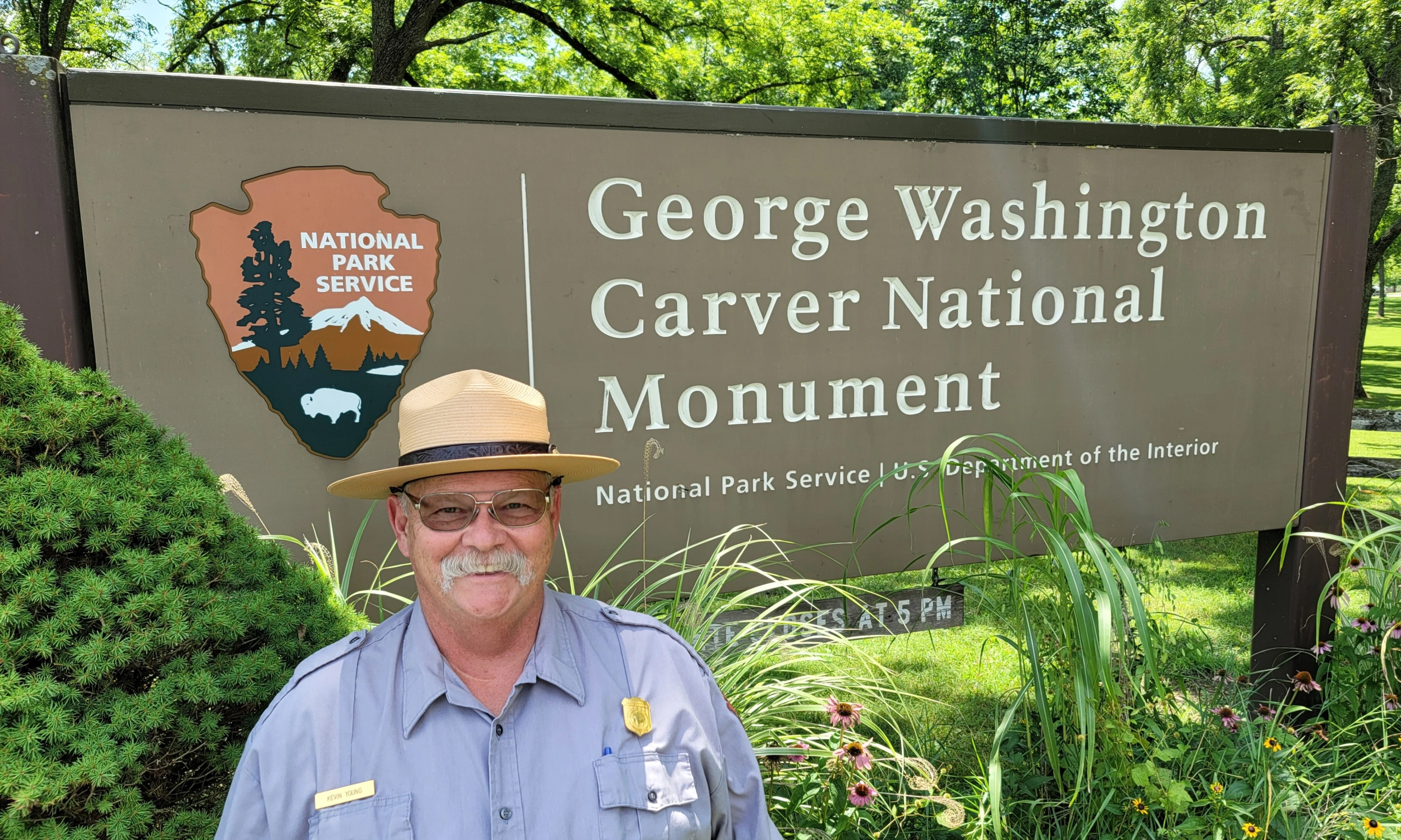 Kevin Young A smiling man in uniform with a white mustache stands in front of a sign for George Washington Carver National Monument.