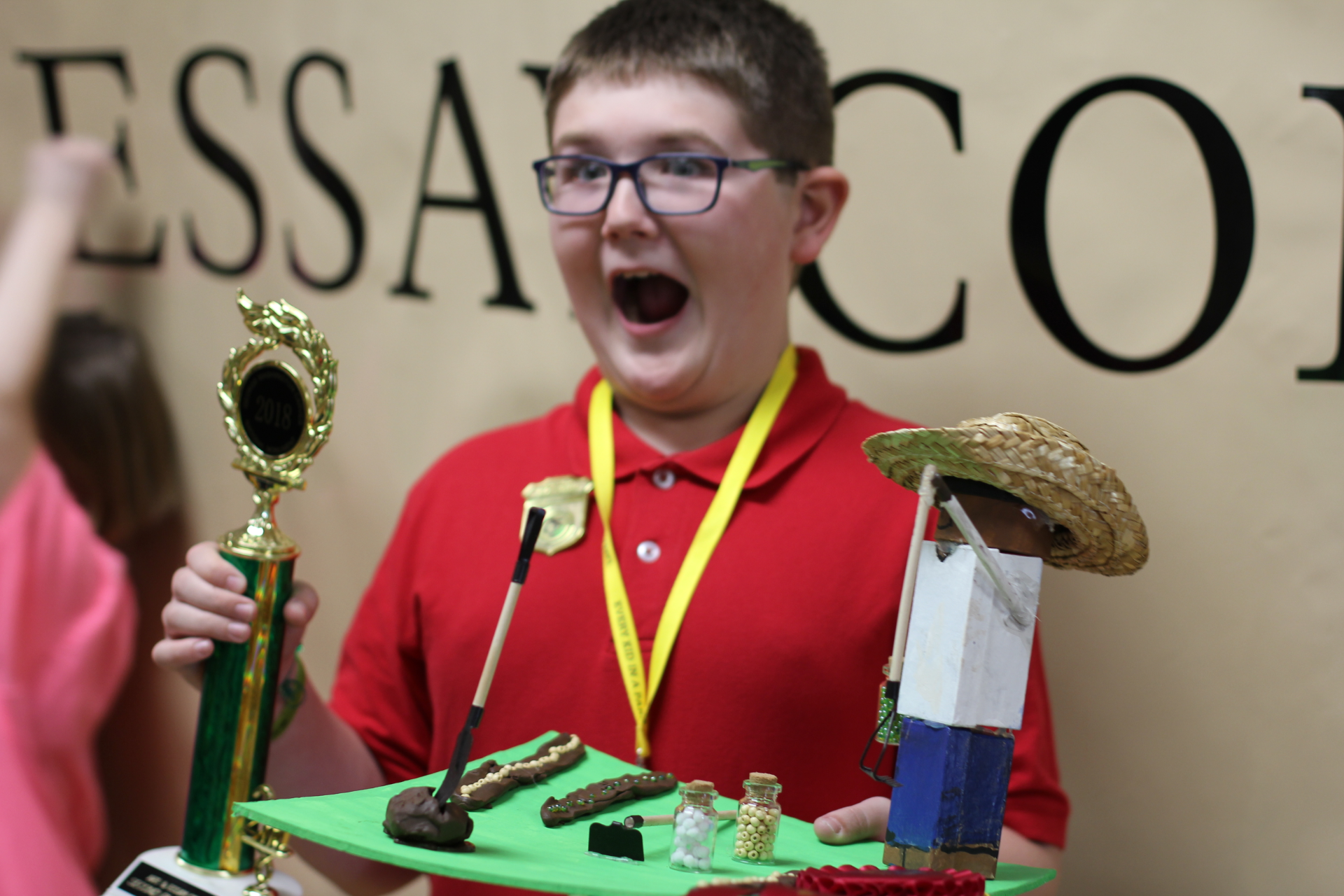 Art and Essay Contest 2024 A student wearing a red shirt and holding his winning art project.