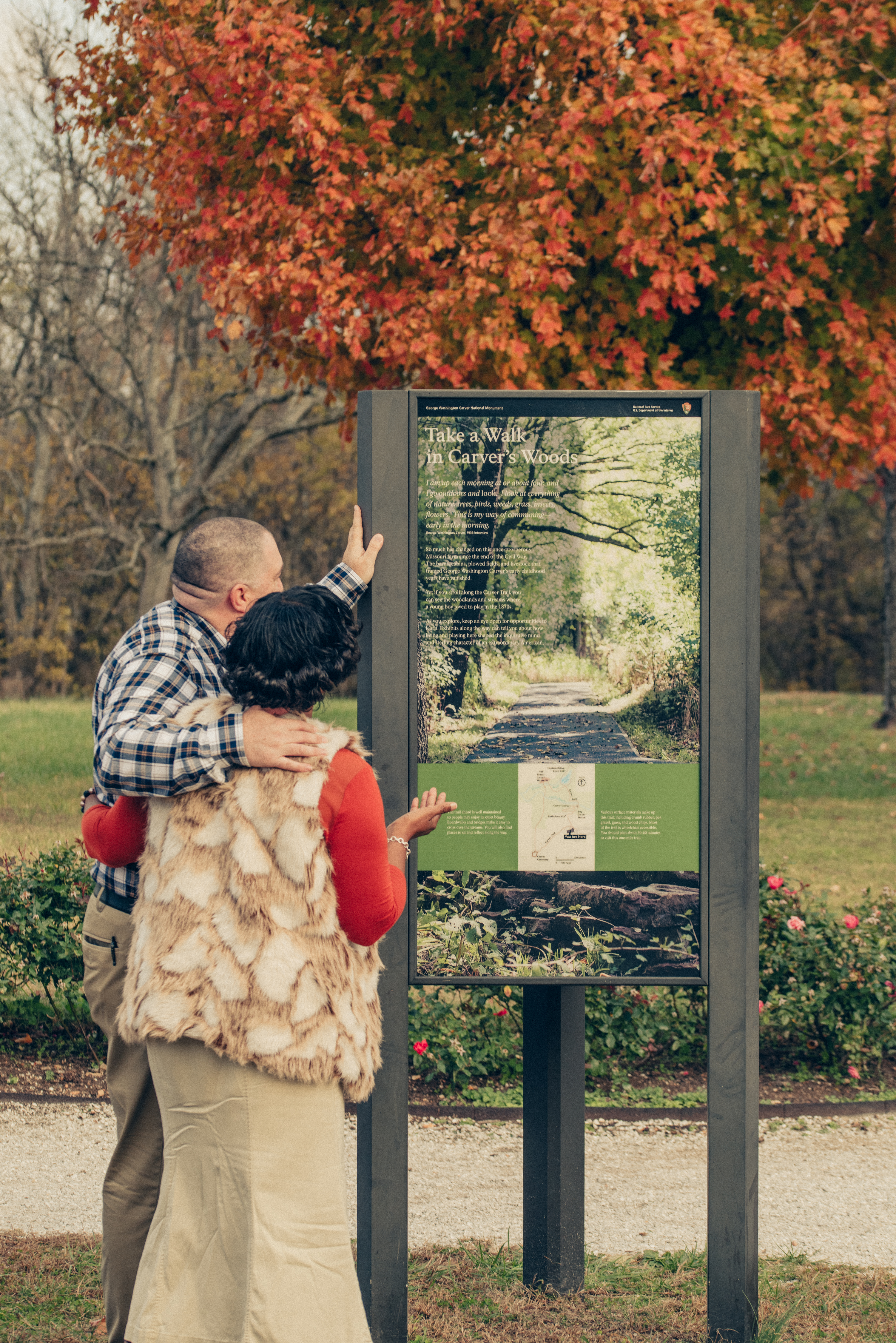 A man and woman outside looking at a map on a park display.