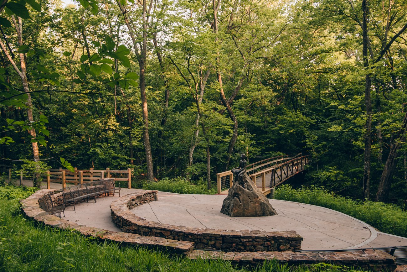 Statue of young George Washington Carver and green woodlands.