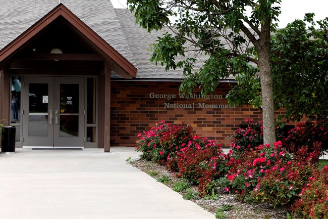 Outside entrance photograph of visitor center with red roses in the landscape.