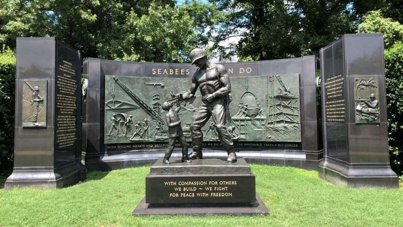 A memorial with a statue of a large soldier greeting a little boy.