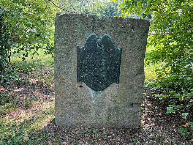 A plaque attached to a stone.