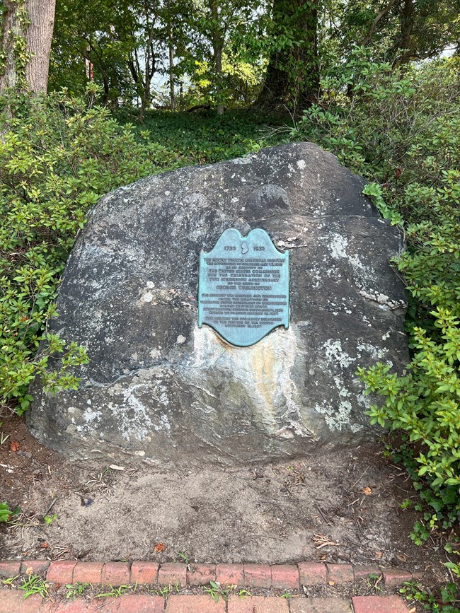 A bronze plaque attached to a boulder.