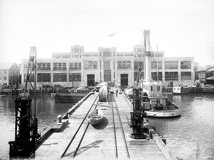Cranes and tug boats wait for freshly made torpedos at the Torpedo Factory dock