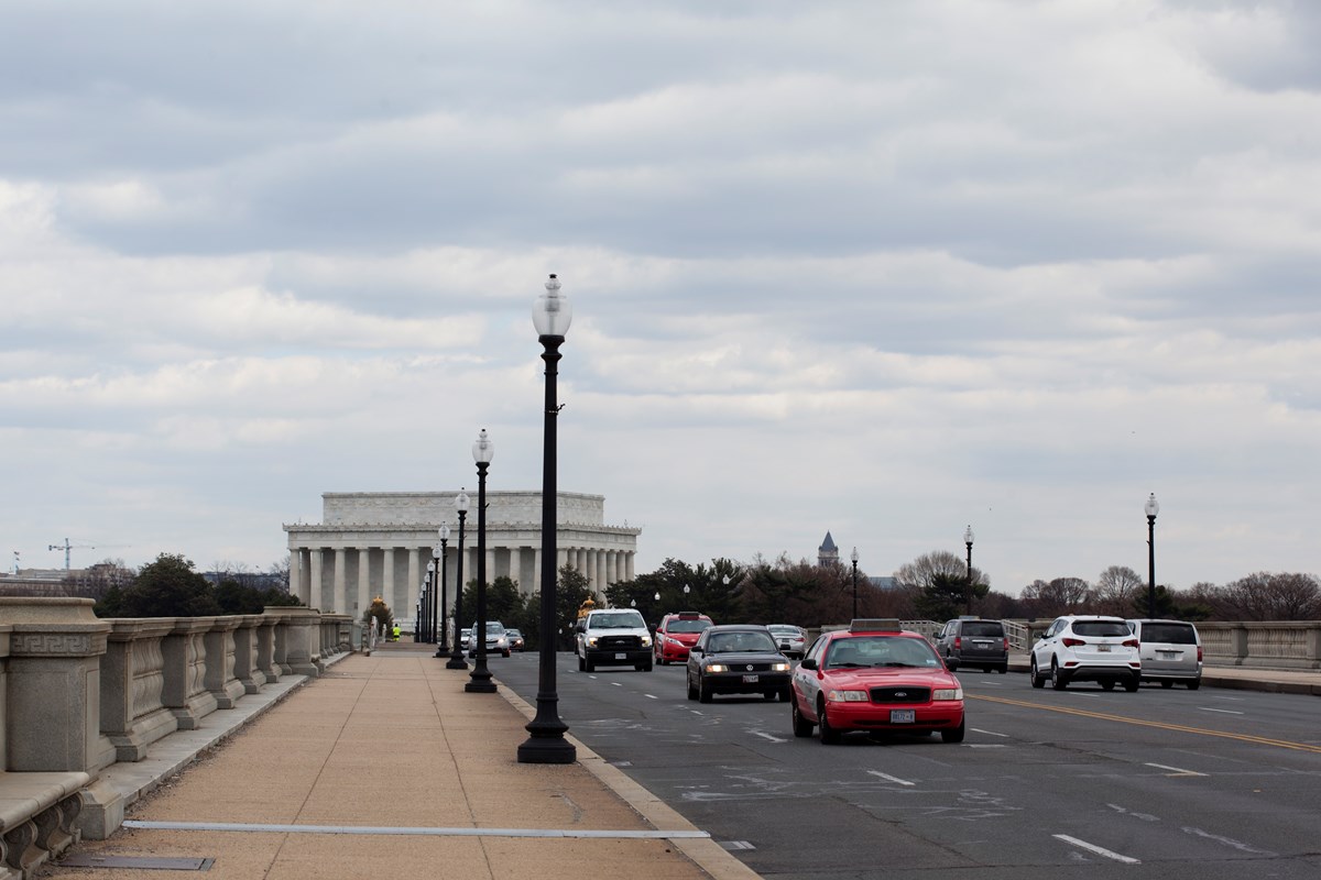 Road deck of Arlington Memorial Bridge. Arlington Memorial Bridge with several cars and the Lincoln Memorial and Washington Monument in the distance.