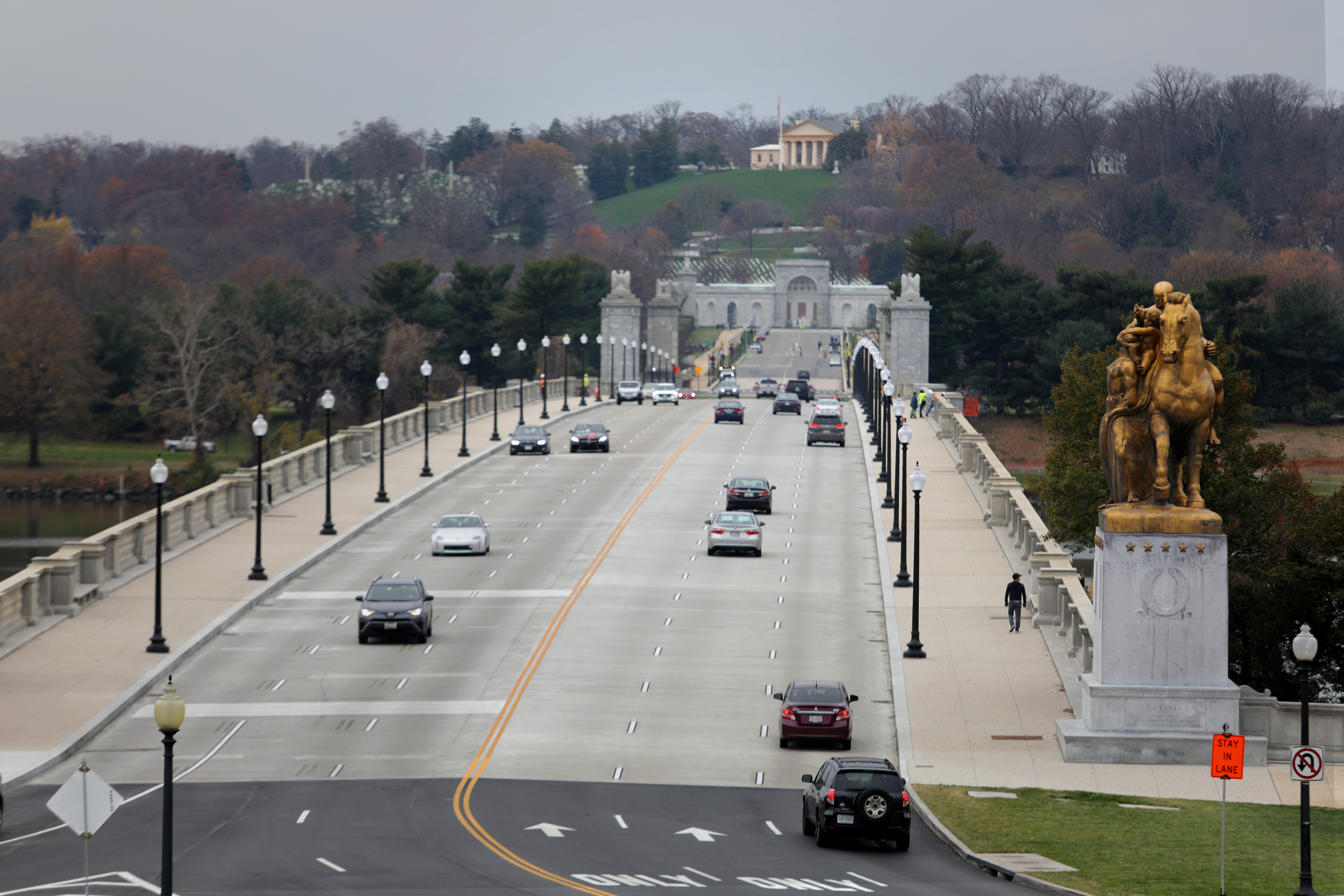 Cars drive in lanes and people walk on sidewalks.