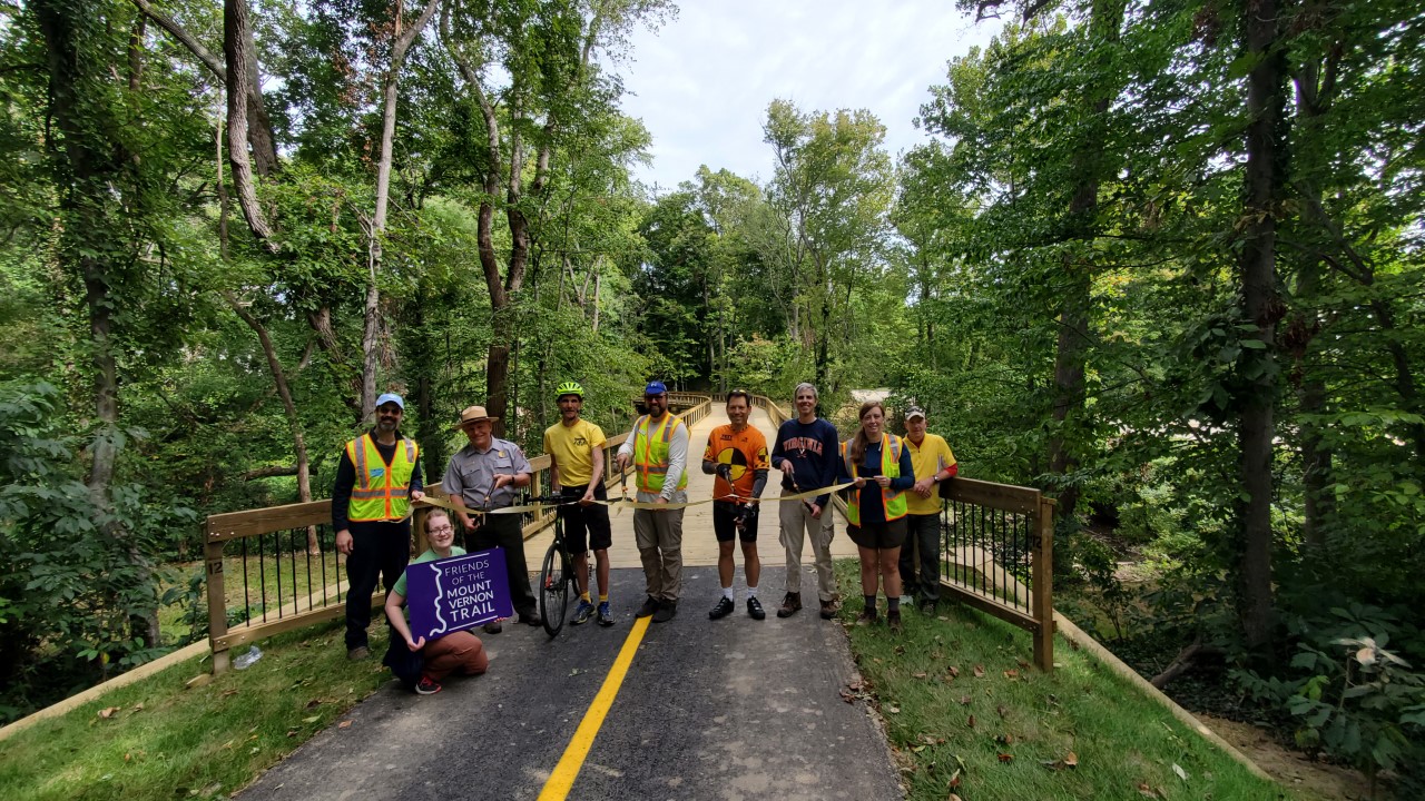 A group of officials cut a ribbon on a park trail