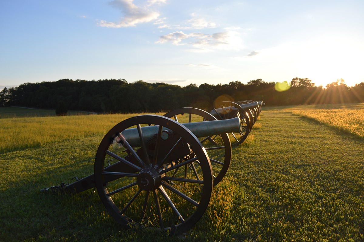 row of civil war cannons at sunset