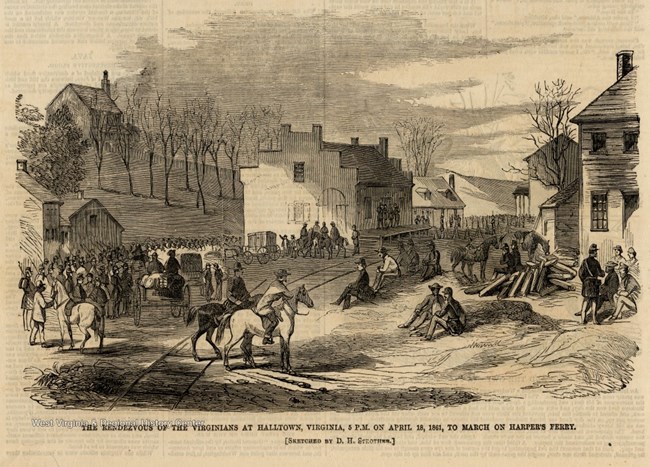armed men on foot and horseback mill around a small town with railroad tracks and a train station