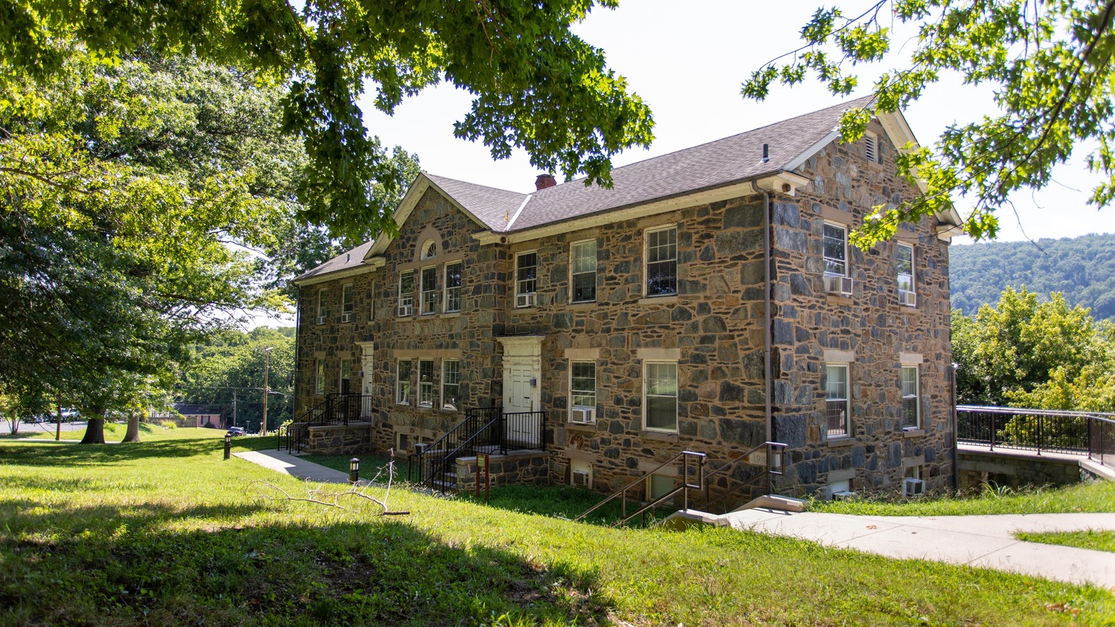 A large stone building surrounded by sidewalks and lawn.