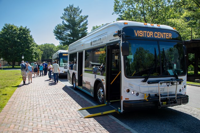 A shuttle bus with a ramp extended on to the sidewalk.